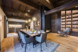 Dining table and open kitchen with fireplace and rocking chair at Nidus Penthouse in Lech