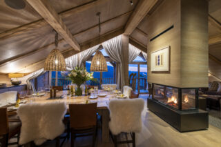 Open fireplace next to the dining table Chalet la Loze in Méribel