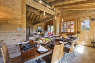 Dining table set for breakfast with door leading to balcony at Chalet Bibi in Verbier