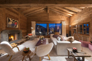 Lounge area with open fireplace in the evening at Chalet Bibi in Verbier