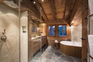 Master en suite bathroomwith oval bath tub, separate shower and twin sinks at Chalet Bibi in Verbier