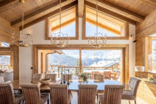 Dining room with double height windows and view over Verbier toward the Combins massif at Chalet les Étrennes in Verbier