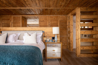 Double bed with mirrored bedside cabinet and en suite bathroom at Chalet les Étrennes in Verbier