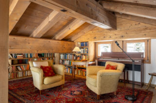 Mezzanine library with armchairs and piano at Chalet les Étrennes in Verbier