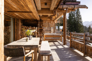 Outdoor dining table and sofas on the balcony at Chalet Pierrier in Verbier on a sunny day