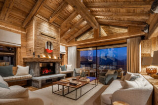 Lounge area with wood-burning fireplace at dusk at Chalet Pierrier in Verbier