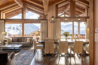 Living and dining area with high ceilings and full height windows at Chalet Sirocco in Verbier