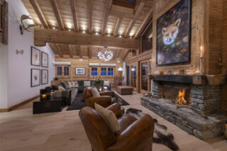 Living space with. armchairs in front of the open fireplace and L-shaped sofa in lounge area at Penthouse Treize Etoiles in Verbier