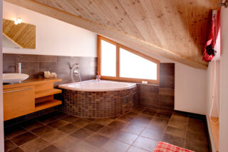 Ensuite bathroom with corner bath tub in bedroom 4 at Chalet Gemini in Zermatt