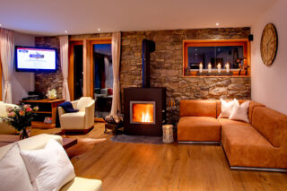 Lounge area with fireplace and corner mounted flat screen TV at Chalet Gemini in Zermatt
