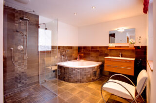 Master bedroom en suite bathroom with corner bath tub and walk-in showrt atChalet Gemini in Zermatt