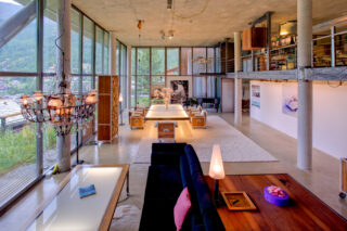Living space with chandelier, suspended table and mezzanine level at the Heinz Julen Loft in Zermatt