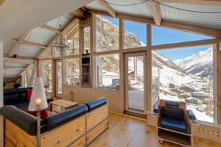 Floor to ceiling windows with views over Zermatt in the living space at the Heinz Julen Penthouse in Zermatt