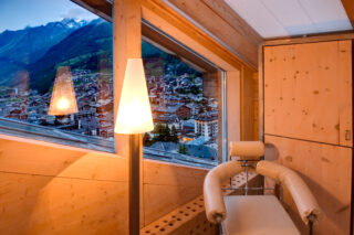 Corner detail with chair and view down to the centre of Zermatt from the master bedroom at the Heinz Julen Penthouse