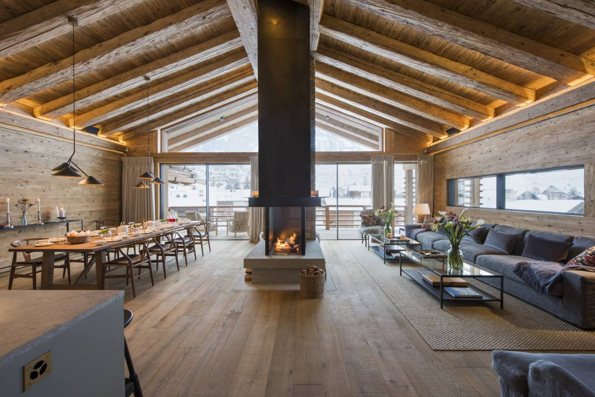 Open-plan living an dining area with double height ceilings and mountain views at Chalet McKinley in Zermatt