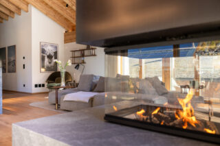 Wood burning island fireplace with glass screen at at Penthouse Weissmatten in Zermatt